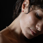 Close-up of a spinel earring and gold chain against a dark background