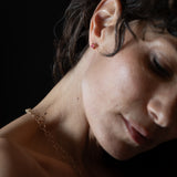 Close-up of a spinel earring and gold chain against a dark background