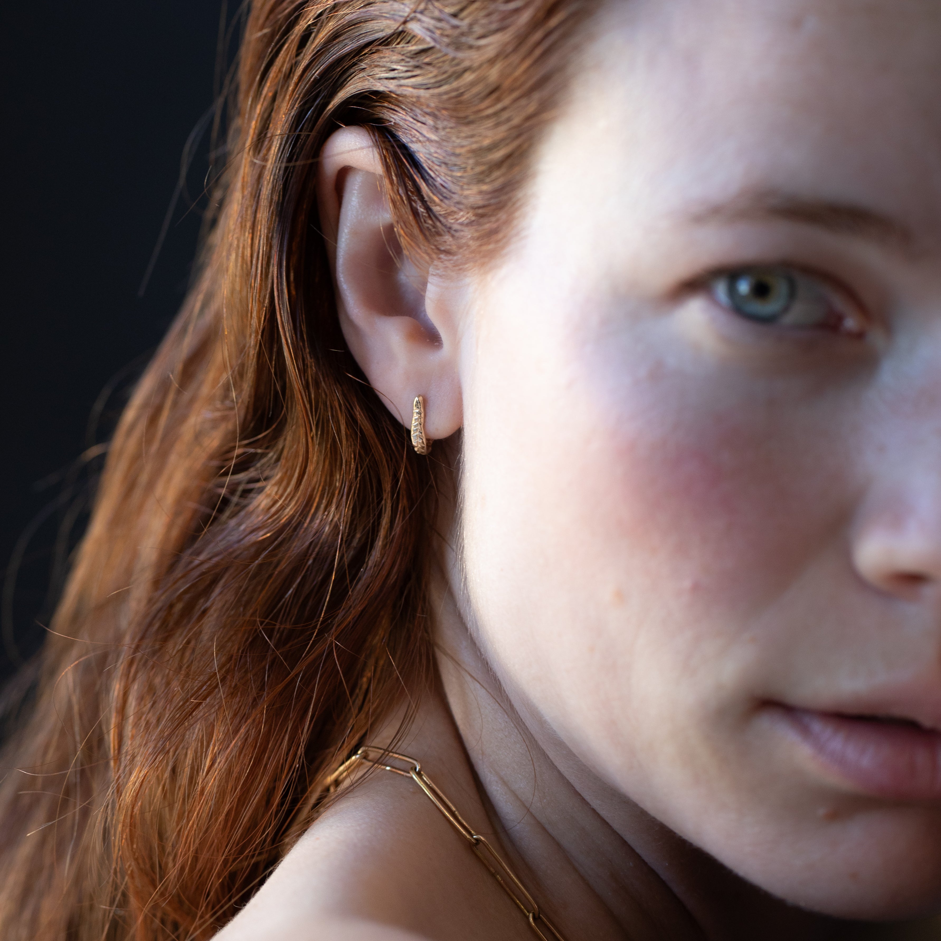 Close-up of Hand-Carved Crooked Fern Huggie Hoops with Sculptural Design