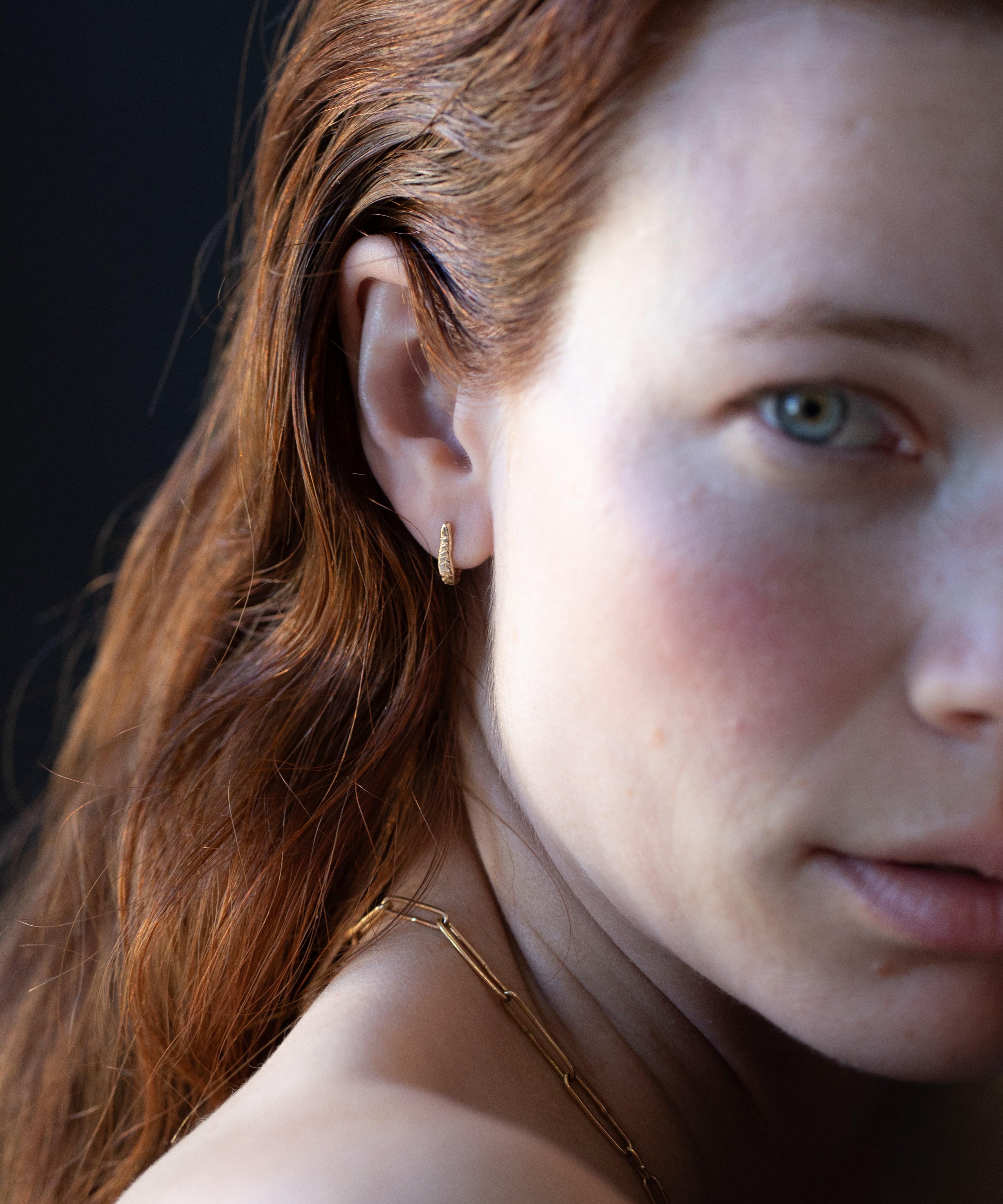 Close-up of Hand-Carved Crooked Fern Huggie Hoops with Sculptural Design