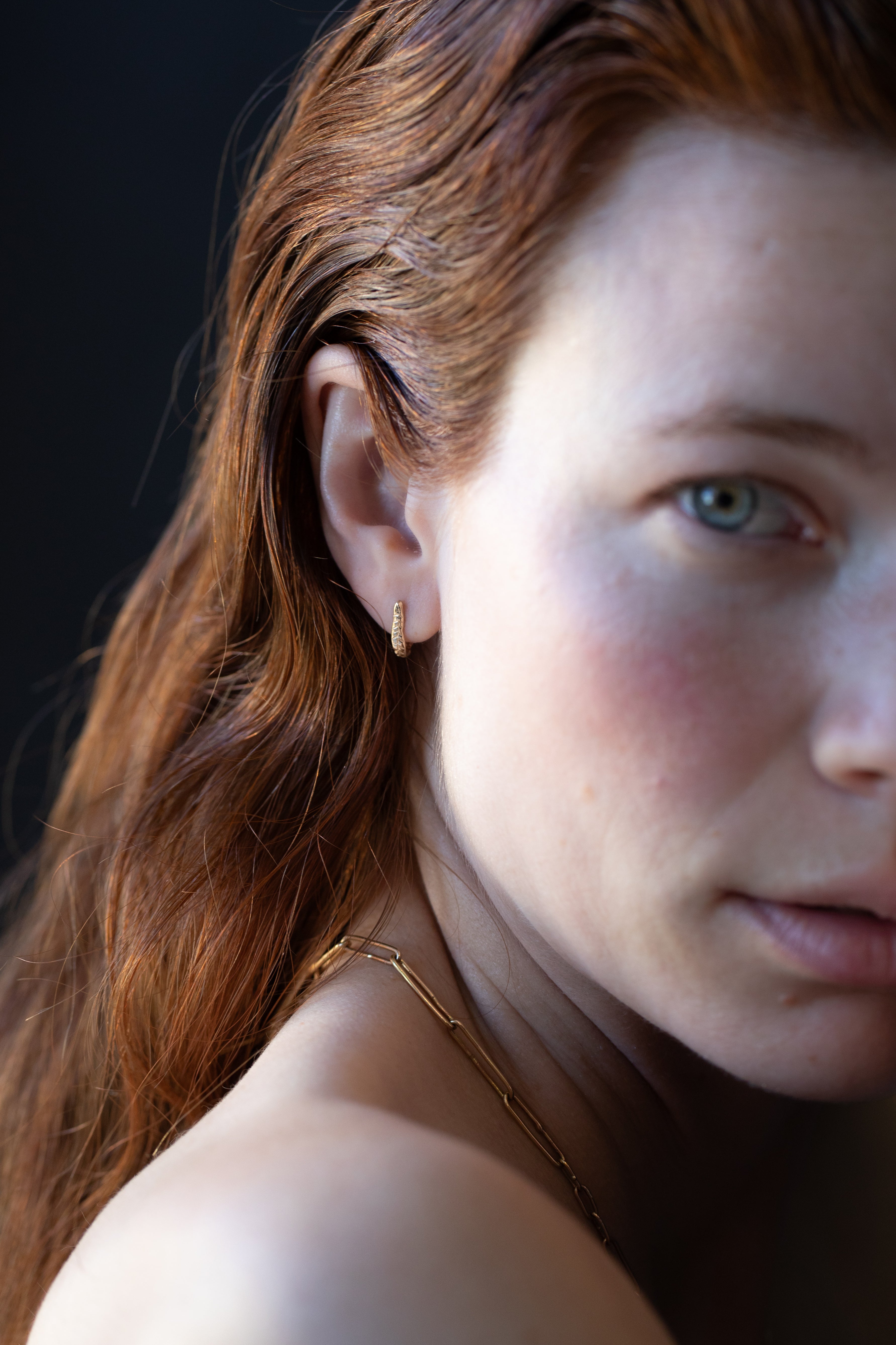 Close-up of Hand-Carved Crooked Fern Huggie Hoops with Sculptural Design